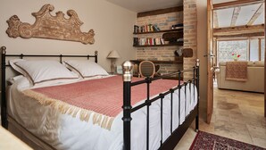 A bedroom with a bed, a bookshelf, a window, and a door leading to another room.