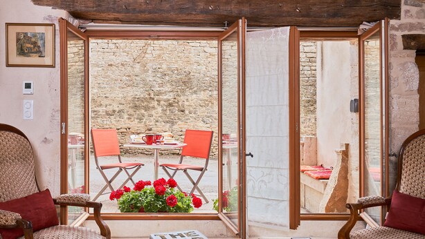 A cozy room with a large window, two wooden chairs, a small table, and a book titled "THE MAP BOOK".