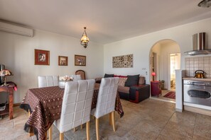 A dining area with a table set for four, a sofa, and a kitchen with an oven and a range hood.