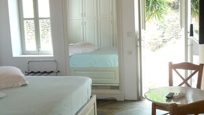 A bedroom with a bed, a chair, a wardrobe, and a door leading outside.