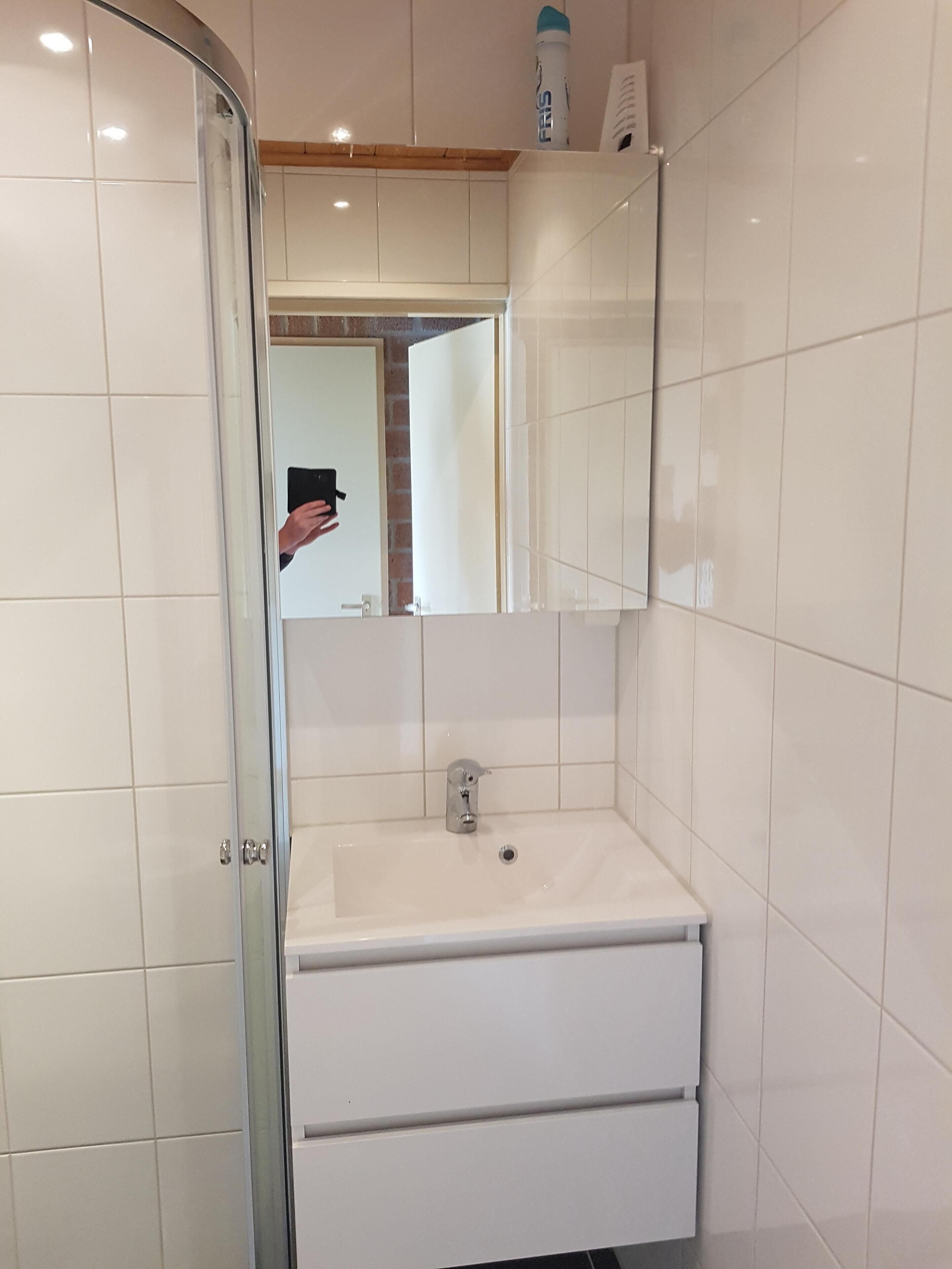 A bathroom with a white sink, a mirror, and a shower area.