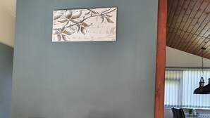 Una habitación con dos sillones grises con cojines estampados, una mesa de comedor de madera con sillas, y una lámpara colgante.