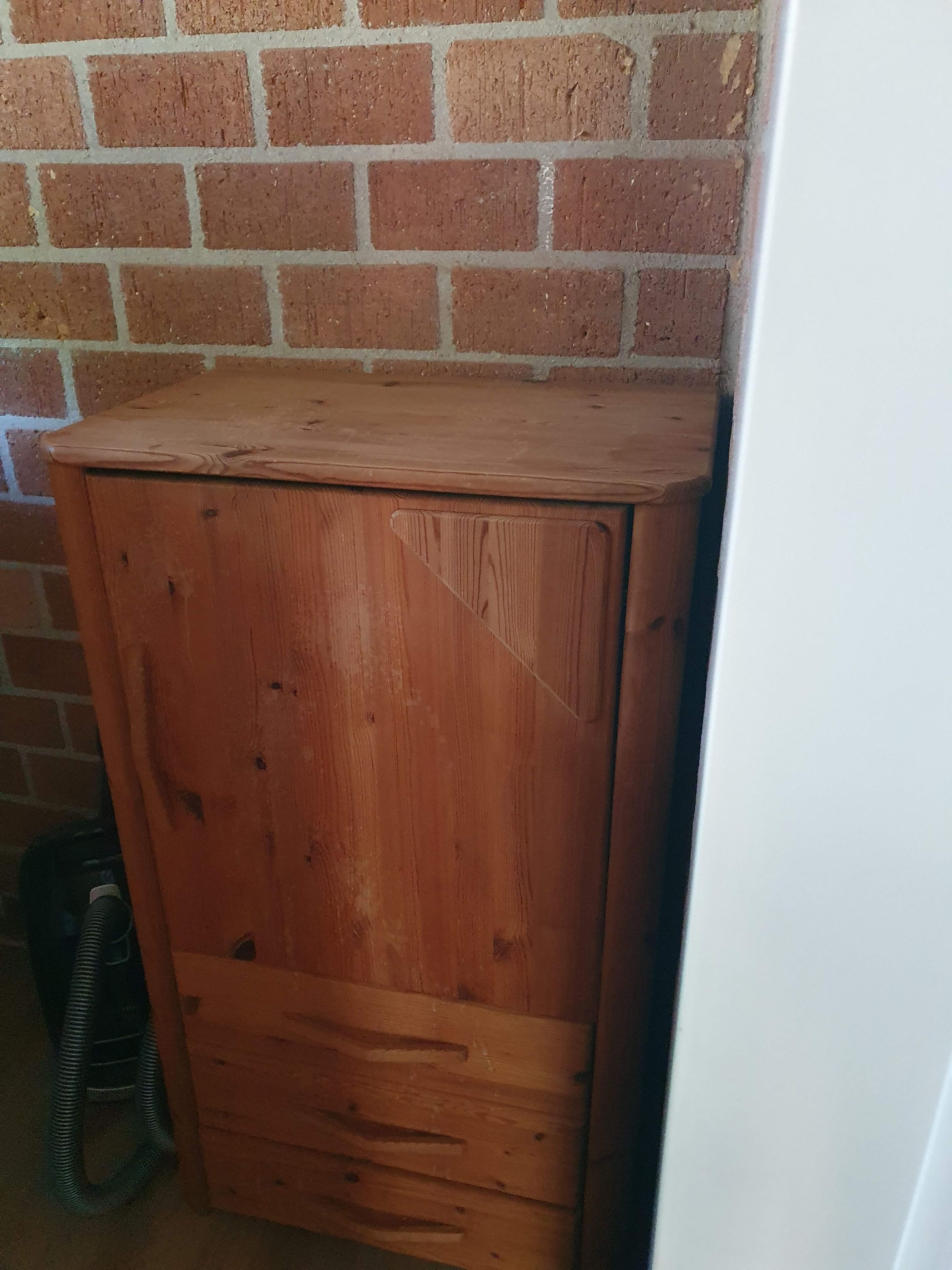 Eine Holzkabine mit einer Schublade, an einer Ziegelwand platziert.