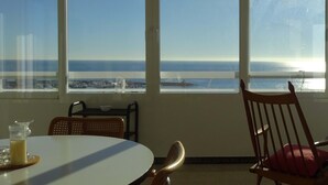 A room with a large window overlooking the ocean, a round table with a glass of juice, and a wooden chair with a cushion. - Beautiful sea view from all rooms, communal swimming pool / tennis (El Campello)
