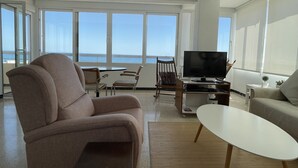 A modern living room with a large window overlooking the sea, a flat-screen TV, a sofa, and a coffee table. - Beautiful sea view from all rooms, communal swimming pool / tennis (El Campello)