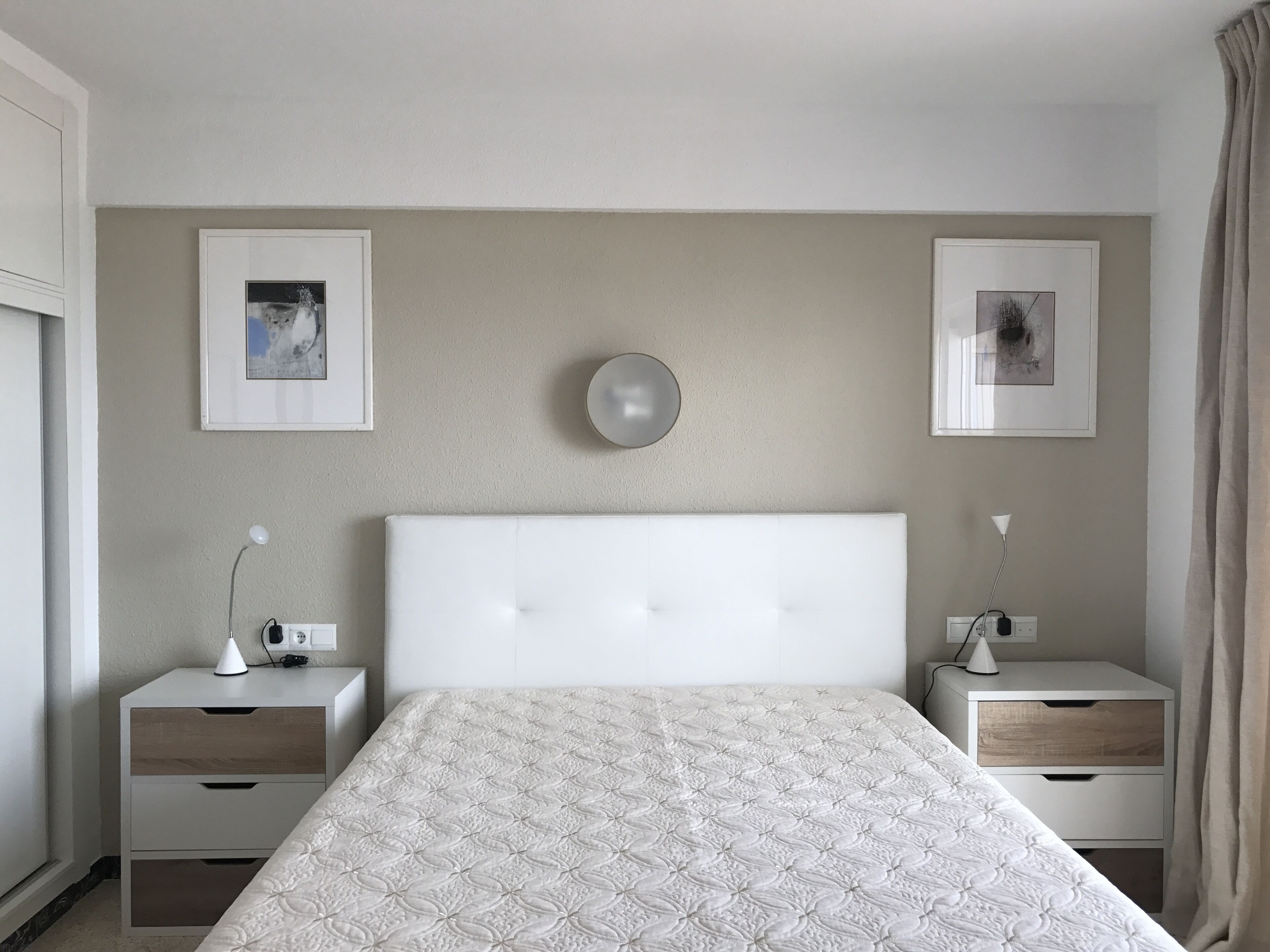 Una camera da letto con un letto grande, due comodini, una sveglia a muro e due quadri incorniciati.