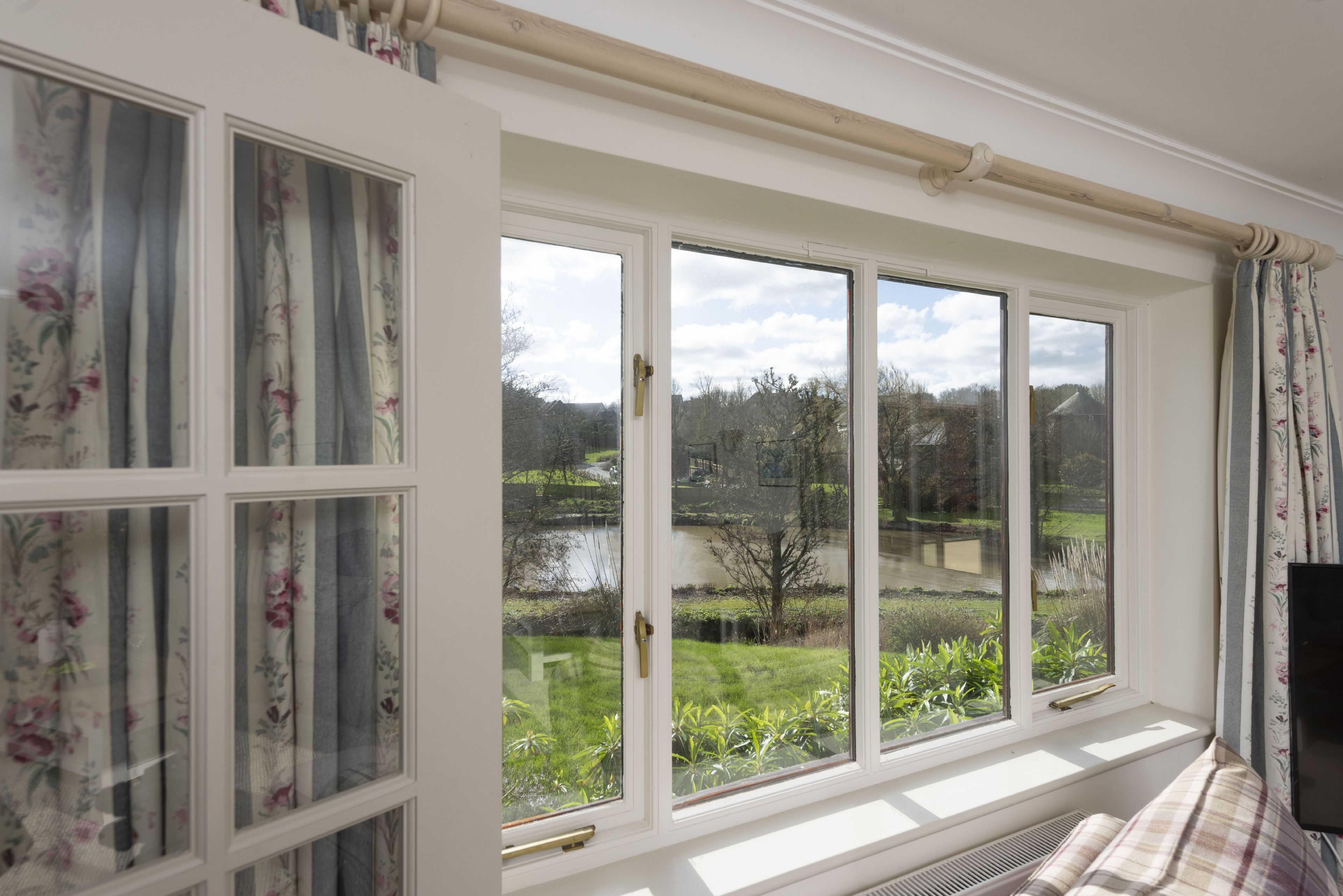 A room with a large window overlooking a garden and a body of water.