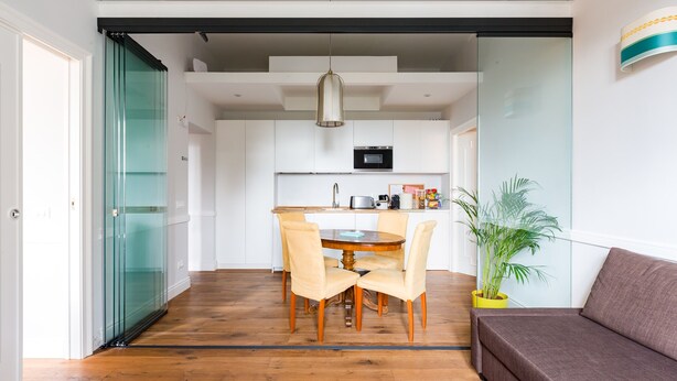 A modern kitchen with white cabinets, a black microwave, and a wooden dining table with chairs.