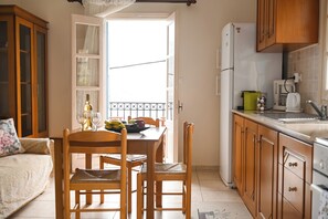 Een gezellige keuken met houten keukenkastjes, een eettafel met stoelen en een koelkast.