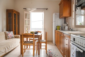 Een keuken met houten kasten, een eettafel met stoelen, een koelkast en een raam.