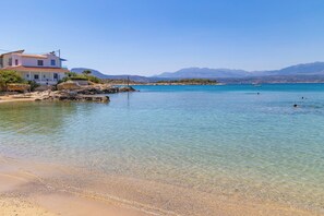 Una proprietà costiera con vista libera sul mare, una spiaggia sabbiosa e montagne sullo sfondo.