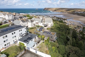 Un quartier résidentiel situé sur la côte, avec des maisons, une plage et une vue sur la mer.