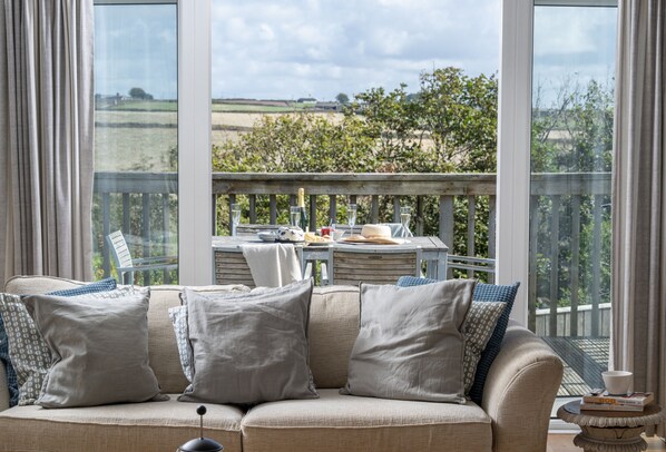 Un balcon accueillant avec un coin salon confortable, une table dressée pour les repas et une vue pittoresque sur la campagne.