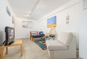 Ein Wohnzimmer mit einer Couch, einem Fernseher, einem kleinen Tisch und einem Teppich.