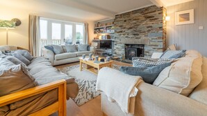 Una sala de estar acogedora con chimenea de piedra, un conjunto de sofá, un televisor y una estantería.