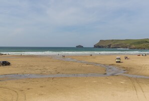 A beach with a sandy shore, a bus, and a few people.