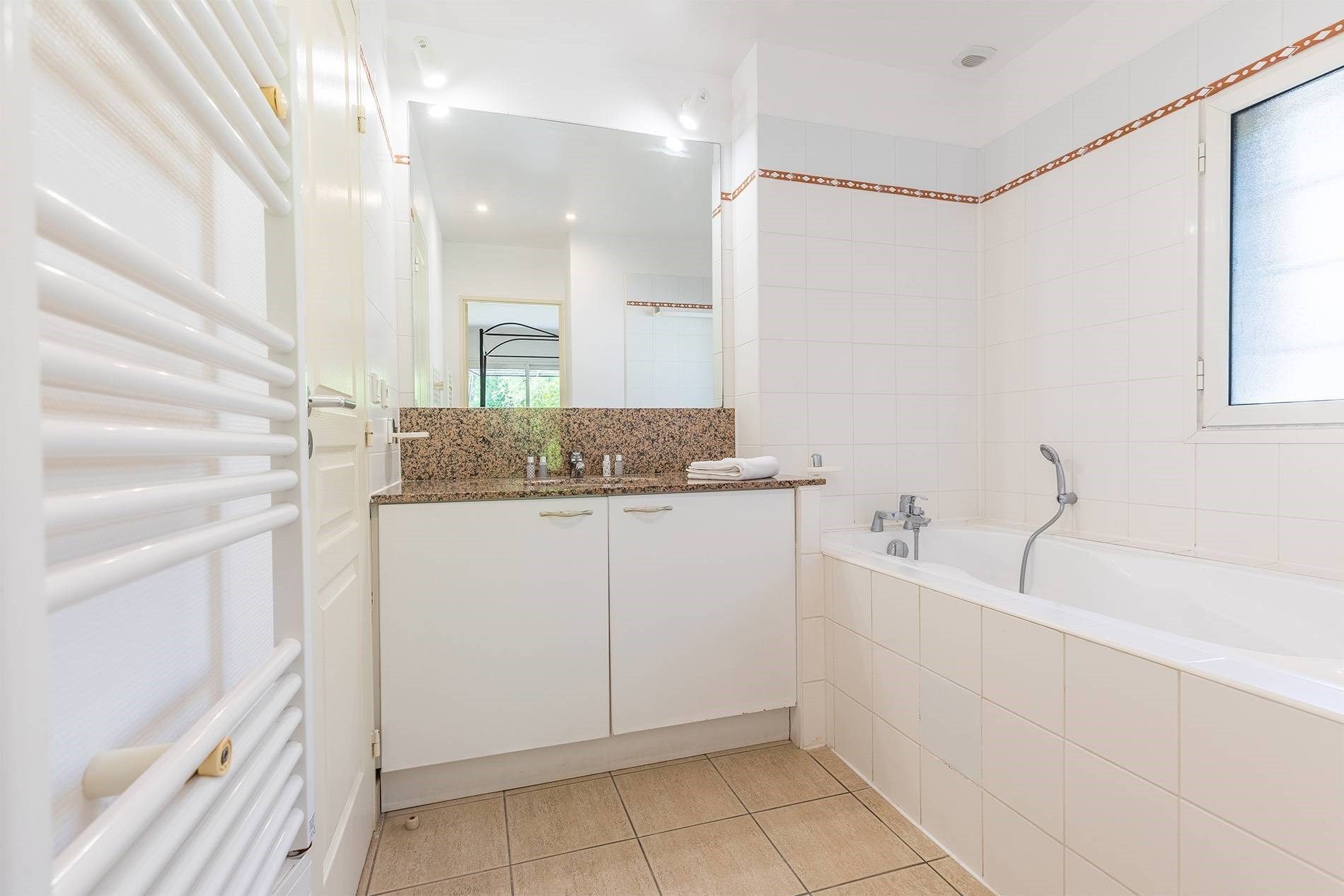A modern bathroom with a white vanity, a shower, and a large mirror.