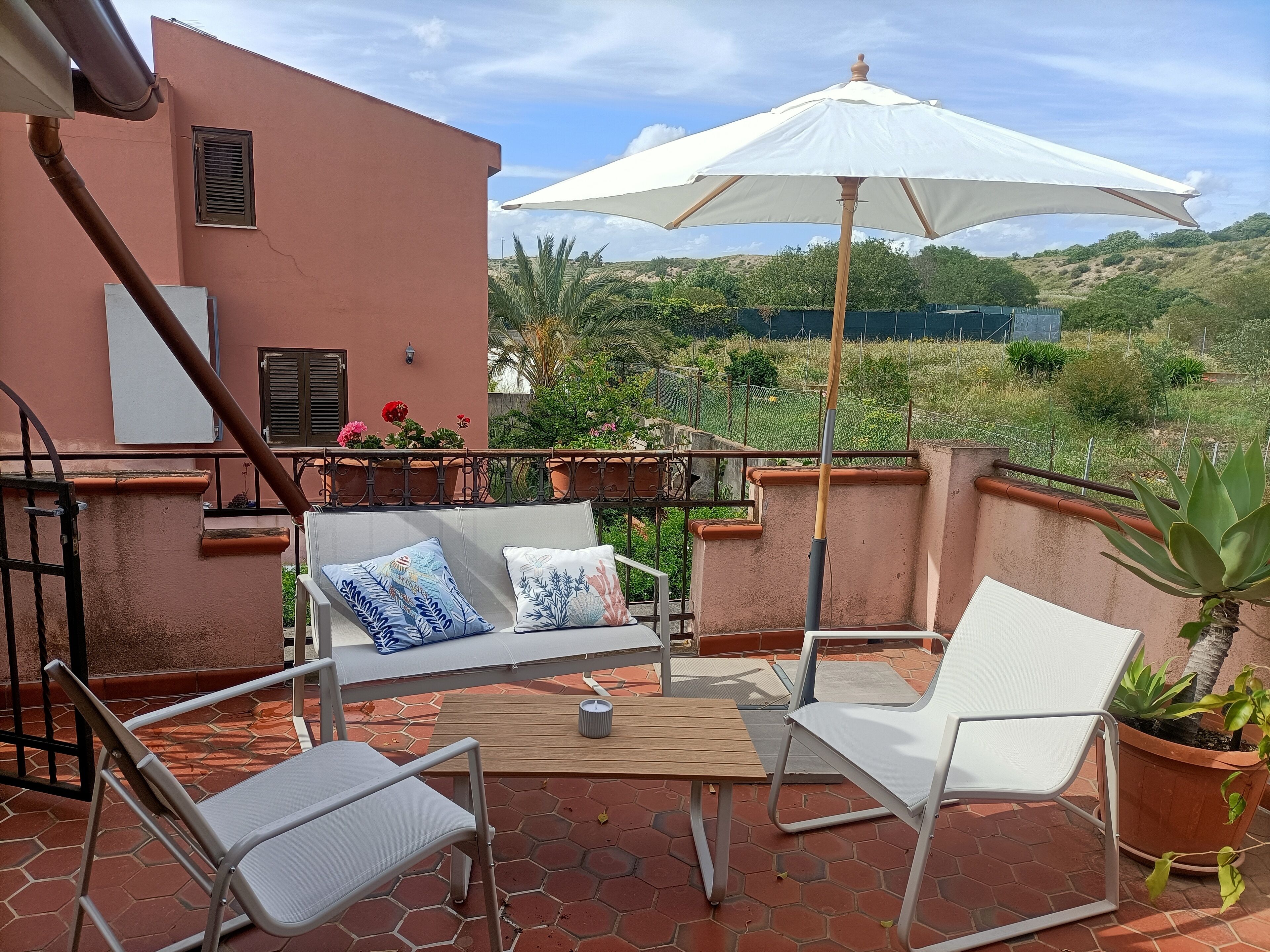 Une terrasse avec une table, des chaises et un parasol.