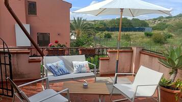 Une terrasse avec une table, des chaises et un parasol.