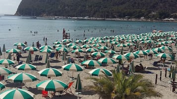 Une plage avec de nombreux parasols et beaucoup de monde.