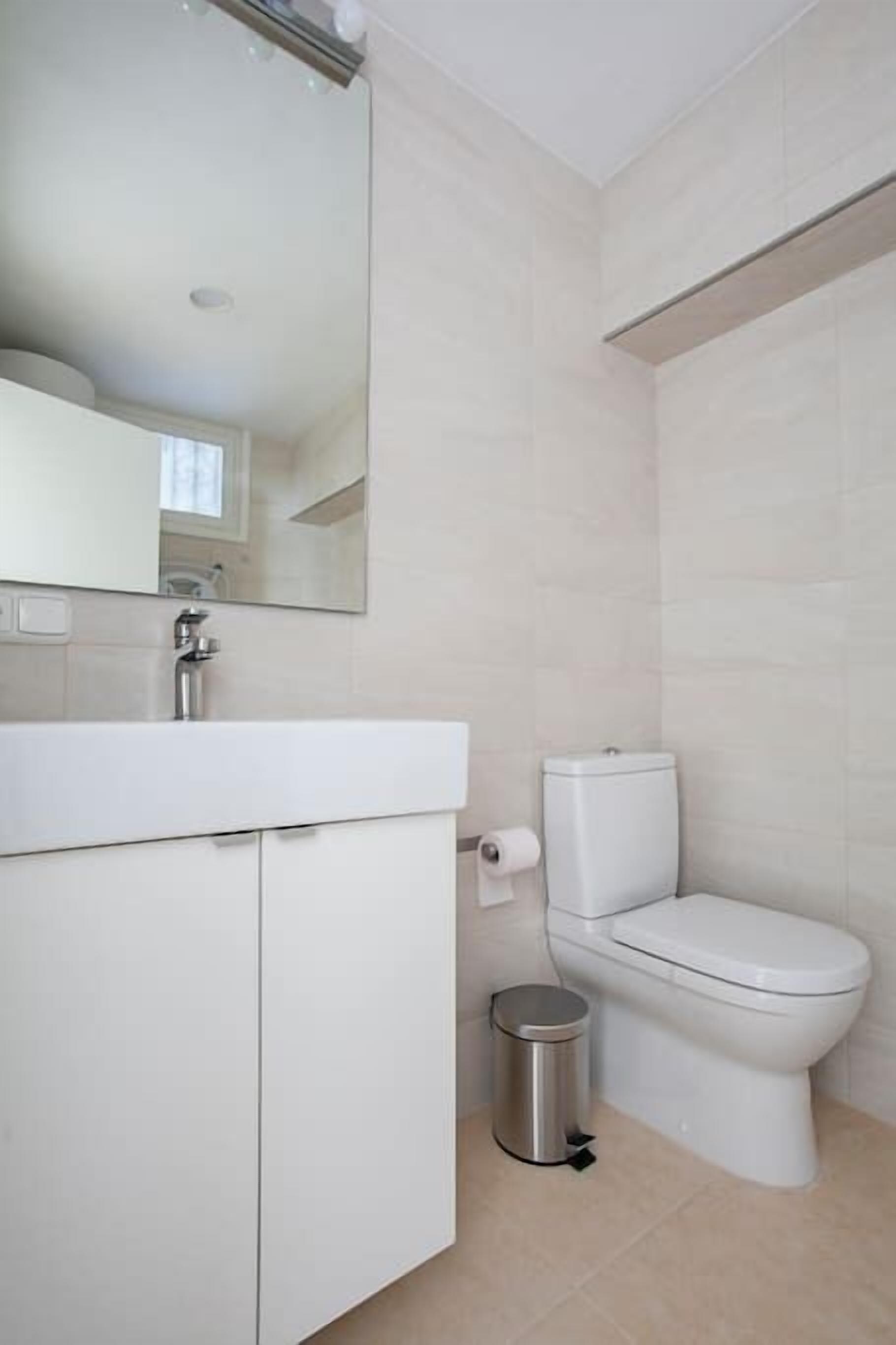 A modern bathroom with a white sink, mirror, and toilet.