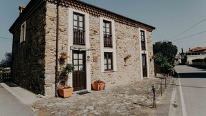 A stone building with a cobblestone street, a wooden door, and a small balcony. - La casa del Campo, cozy cottage next to the beaches of Cudillero (Cudillero)