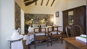 A cozy room with a stone wall, wooden furniture, and a bed with pillows. - La casa del Campo, cozy cottage next to the beaches of Cudillero (Cudillero)
