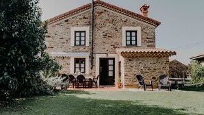 A stone house with a tiled roof, a front door, and a small porch with two chairs. - La casa del Campo, cozy cottage next to the beaches of Cudillero (Cudillero)