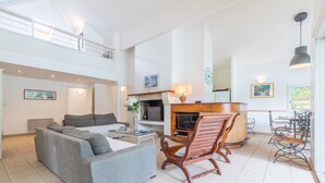 A spacious living room with a grey sofa, wooden chair, and dining table. - Villa Spacieuse et Moderne Avec Piscine Privée! (Moliets-et-Maa)