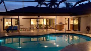 Une piscine avec un patio couvert comprenant des sièges et une table à manger.
