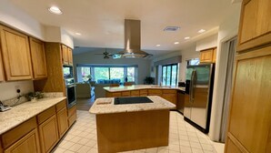 Une cuisine moderne avec des meubles en bois, un îlot central, un four encastré et un réfrigérateur en acier inoxydable.