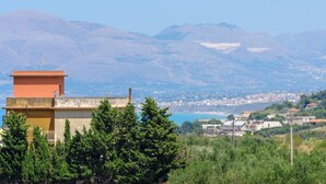 A coastal town with a prominent orange building in the foreground, a clear view of the sea, and a mountainous backdrop. - apartment near the sea (scoppello Guidaloca) (Castellammare del Golfo)