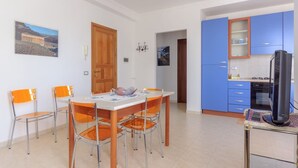 A dining area with a wooden table and chairs, a kitchen with blue cabinets, and a painting on the wall. - apartment near the sea (scoppello Guidaloca) (Castellammare del Golfo)