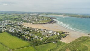 An aerial view of a coastal town with a beach, green fields, and residential areas. - Miss Fishers is a charming two bedroom cottage close to Port Isaac. (Port Isaac)