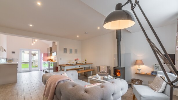 A modern living room with a large grey sofa, a dining area with a wooden table, and a fireplace. - Miss Fishers is a charming two bedroom cottage close to Port Isaac. (Port Isaac)