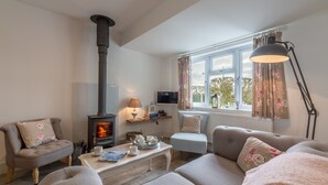 A cozy living room with a fireplace, comfortable seating, and a television. - Miss Fishers is a charming two bedroom cottage close to Port Isaac. (Port Isaac)