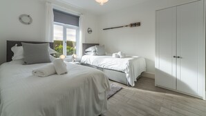 A bedroom with two beds, a wardrobe, and a large window. - Miss Fishers is a charming two bedroom cottage close to Port Isaac. (Port Isaac)