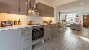 A modern kitchen with a built-in oven, a coffee maker, and a kettle on the counter. - Miss Fishers is a charming two bedroom cottage close to Port Isaac. (Port Isaac)