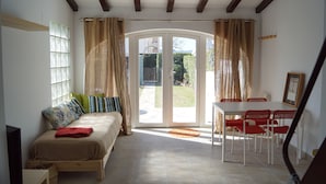 Ein Zimmer mit einem Bett, einem Tisch mit Stühlen und einer Schiebeglastür, die zu einem Außenbereich führt.