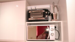 A kitchen with a built-in microwave and a toaster oven on a white shelf. - Self-contained New Studio with independent entrance in an up-market quiet area. (London)