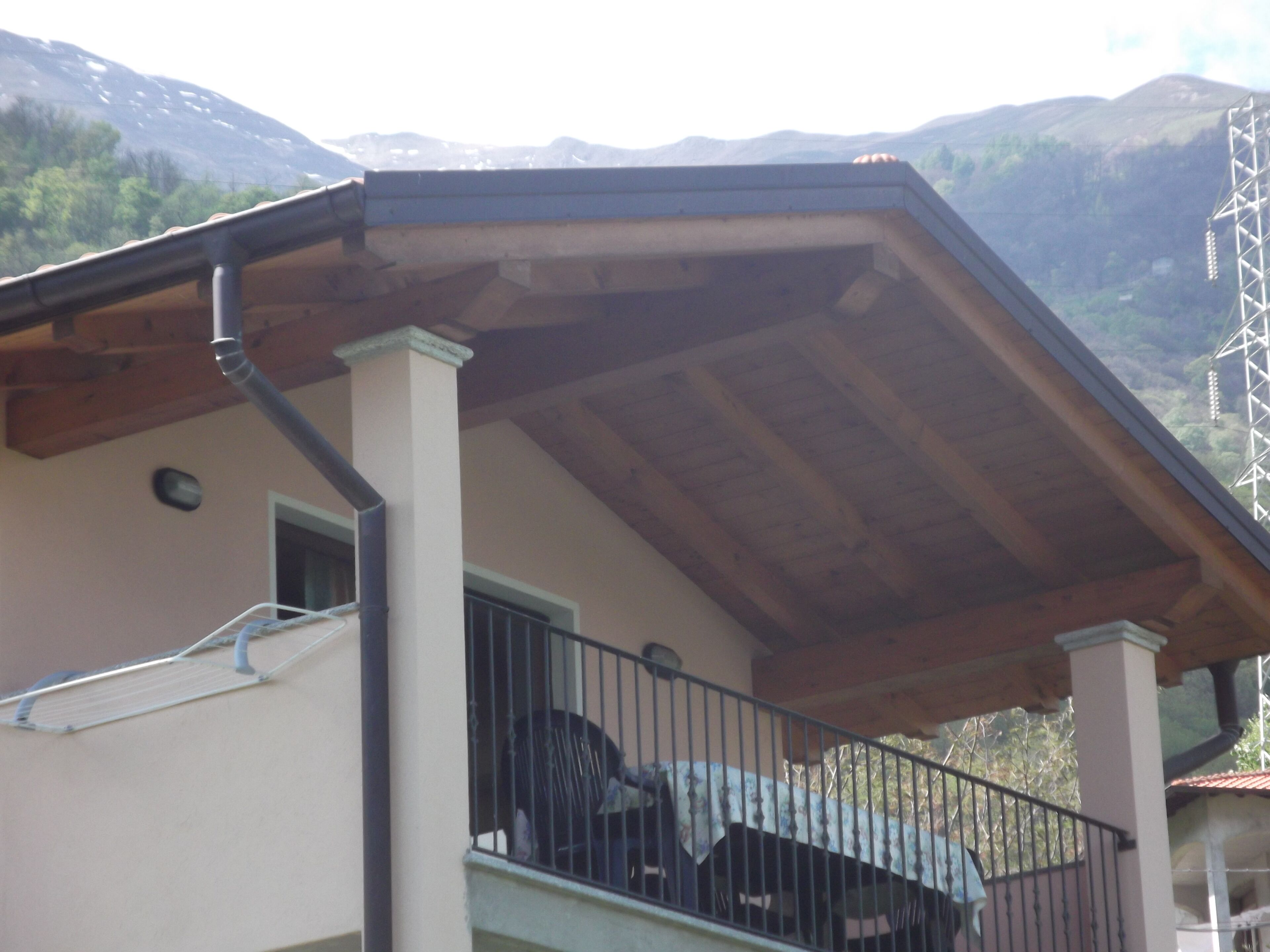 Ein Gebäude mit Balkon, Holzdach und Bergkulisse.