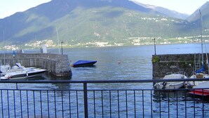 Una marina con barche ormeggiate, un muro in pietra e montagne sullo sfondo.