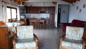 Una cucina accogliente con mobili in legno, un tavolo da pranzo e due sedie con motivo floreale.