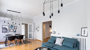 Uma sala de estar moderna com um sofá verde-água, uma área de refeições com mesa e cadeiras e uma cozinha com um radiador.