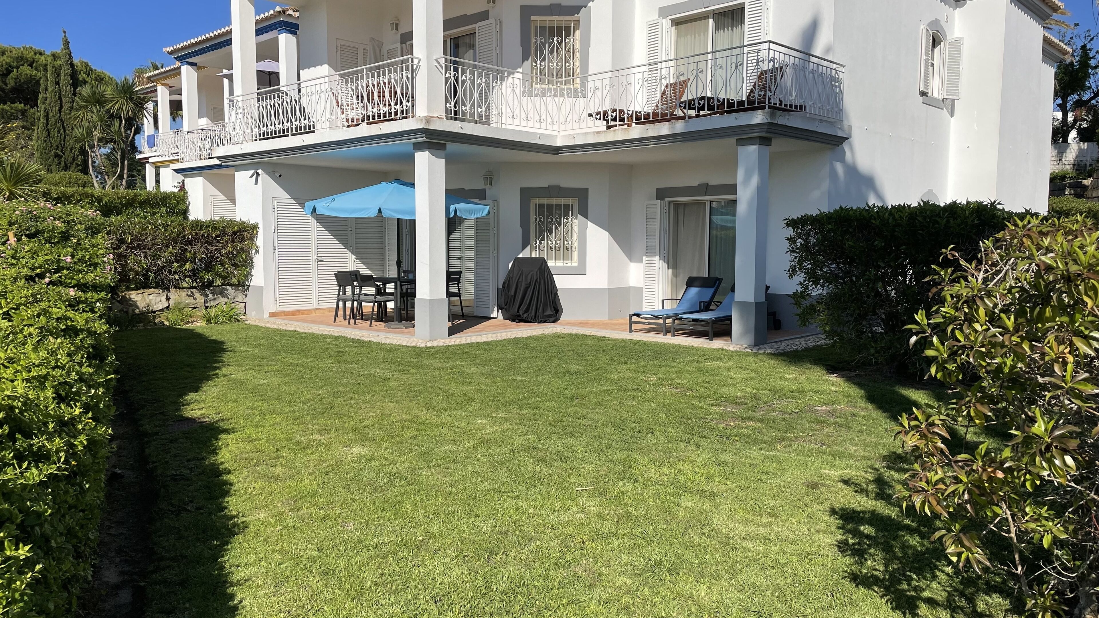 A two-story house with a covered patio, outdoor seating, and a well-maintained lawn.