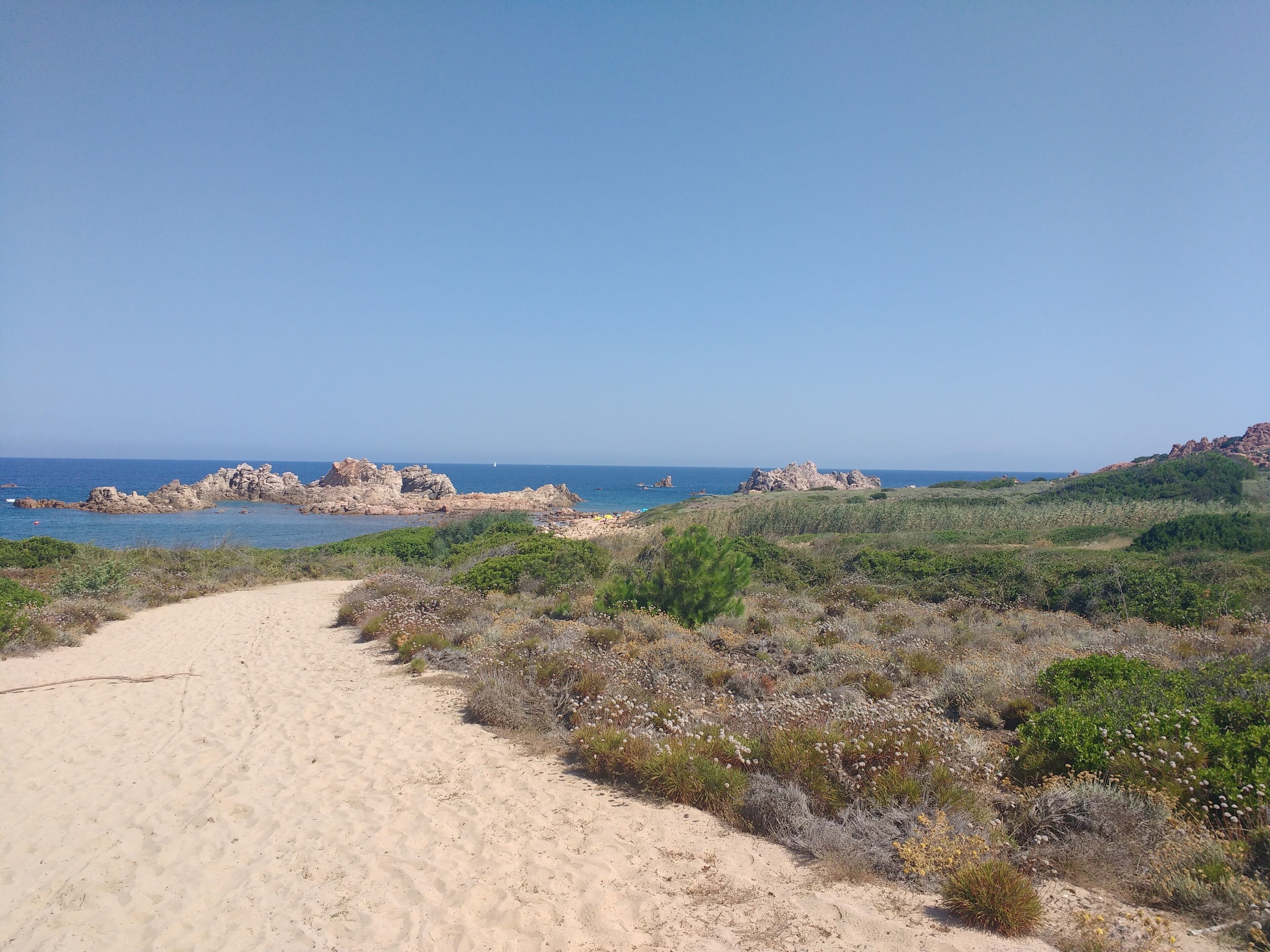 A coastal path leading to rocky outcrops with a clear view of the sea.