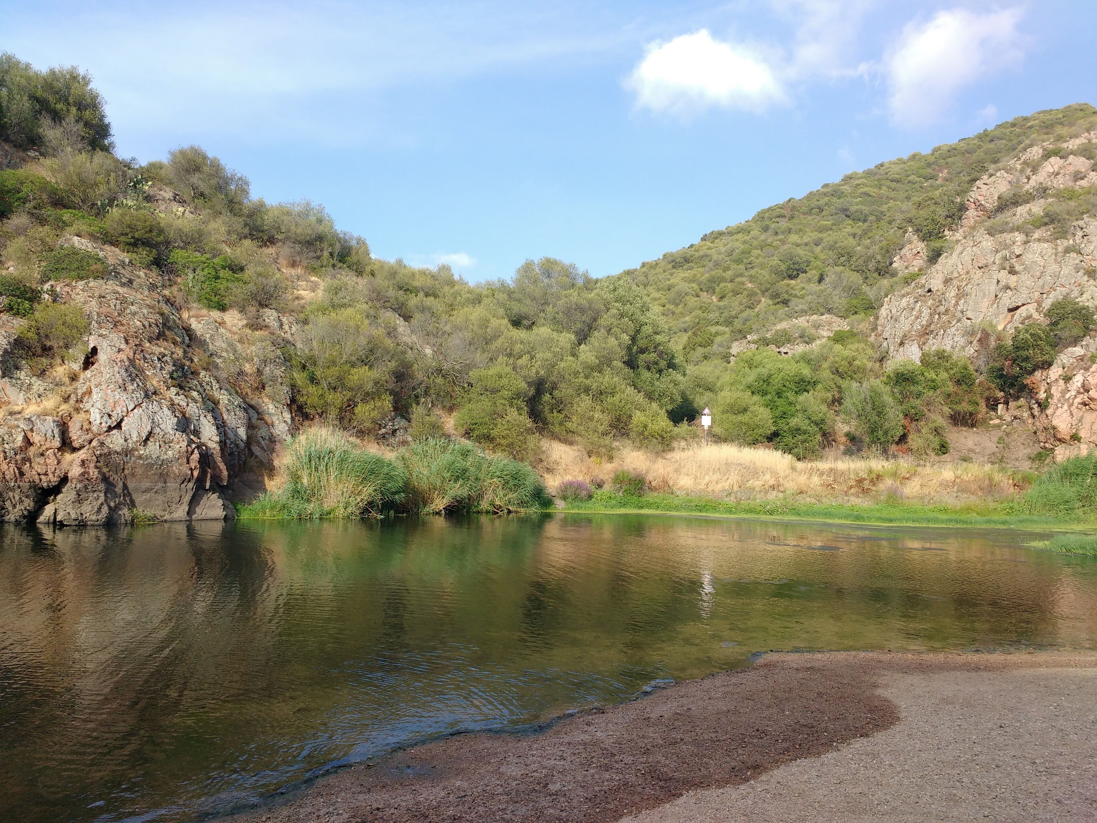 Un paysage naturel caractérisé par une rivière, un terrain rocheux et une végétation luxuriante.