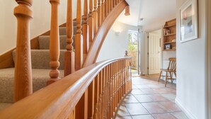 A wooden staircase with a curved handrail leading to a landing. - The Roundhouse has an unusual design and stands alone overlooking the lakes. (Wadebridge)