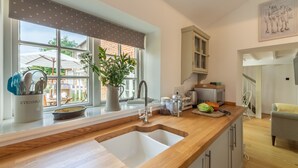 Une cuisine moderne dotée d’un plan de travail en bois, d’un évier à deux bacs et donnant sur le jardin arrière.
