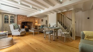 Un salon chaleureux avec une cheminée en briques, un plancher en bois et un escalier.